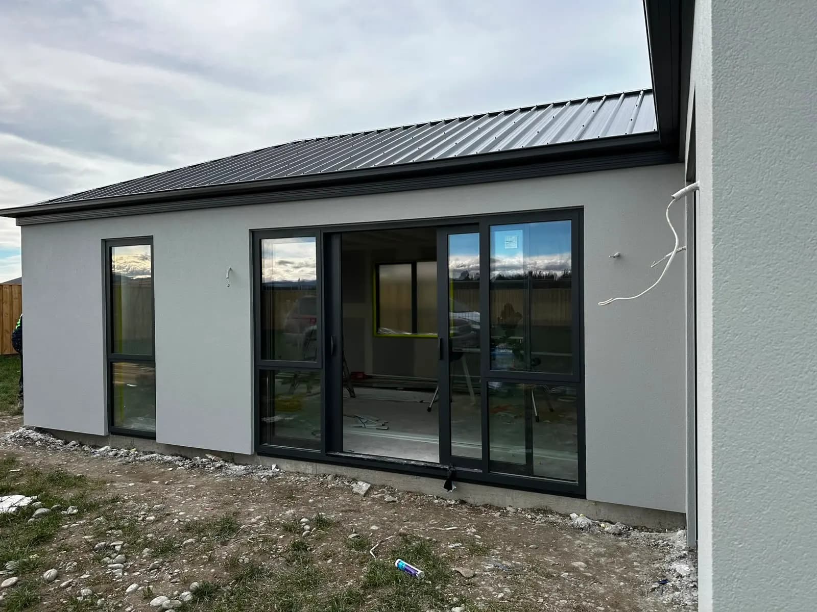 Completed single-storey home with light grey plaster and dark roof