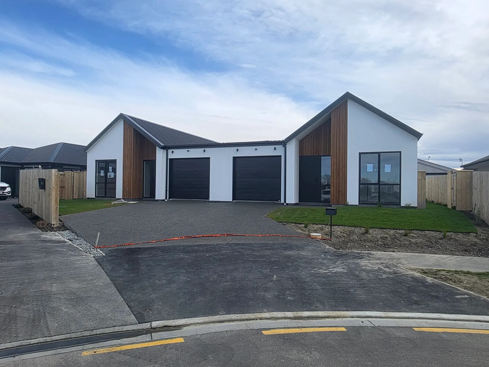 Pair of gable-front homes with white plaster and cedar accents under a blue sky
