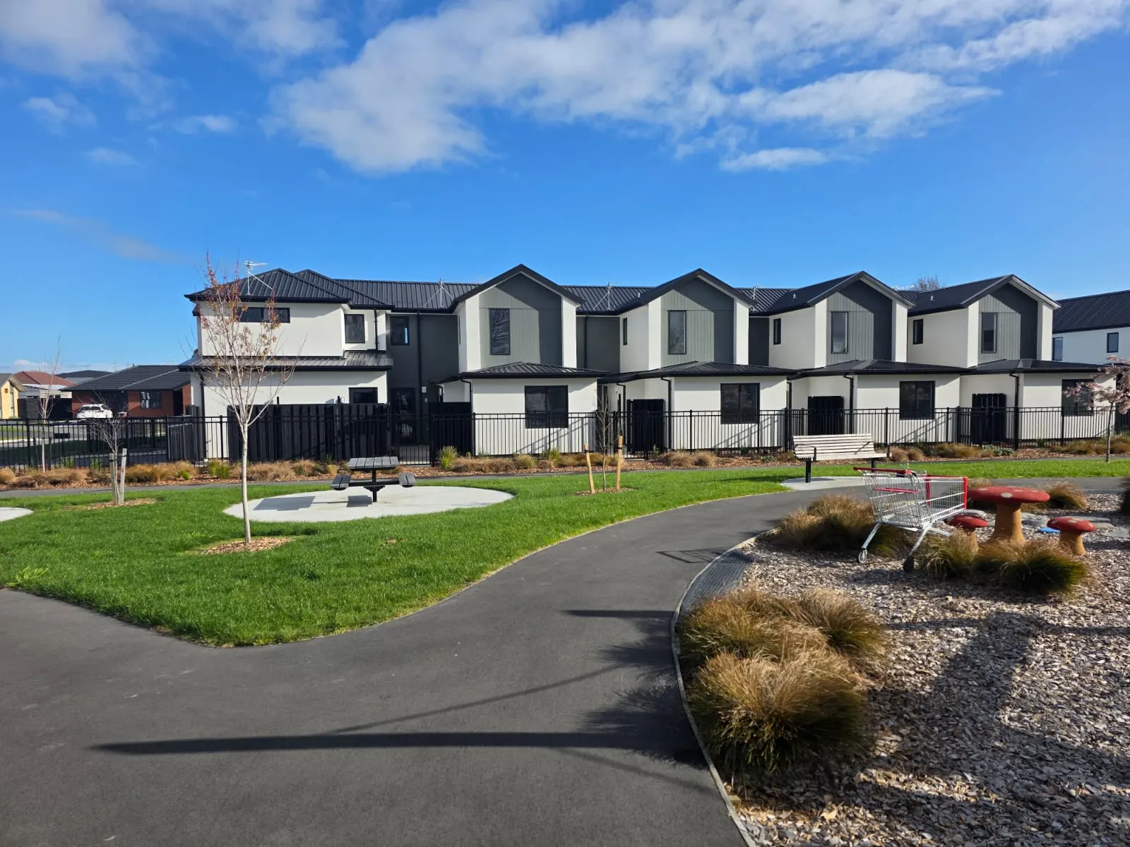 Townhouse development with white plaster and dark cladding around a green reserve